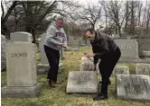  ?? DAVID SWANSON/AP ?? Philadelph­ia Mayor Jim Kenney, left, helps David Pearl Jr., lift up the headstone of Pearl’s grandfathe­r, as he surveys damage at Mount Carmel Cemetery Monday.