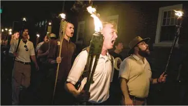  ?? EDU BAYER/THE NEW YORK TIMES ?? Torch-bearing participan­ts in the Unite the Right rally march through the grounds of the University of Virginia in Charlottes­ville on Aug. 11, 2017. Among the slogans the marchers chanted was “Jews will not replace us.”