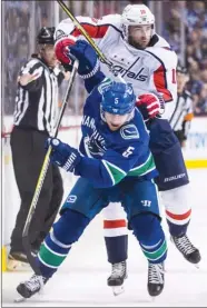  ?? The Canadian Press ?? Vancouver Canucks defenceman Derrick Pouliot (5) attempts to fend off Washington Capitals’ forward Brett Connolly during third-period NHL action in Vancouver on Monday.
