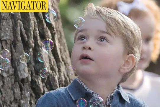  ?? JONATHAN HAYWARD / THE CANADIAN PRESS ?? Prince George reacts to bubbles being blown by his father, Prince William, during a children’s party at Government House in Victoria on Thursday. The organizers pulled out all the stops for the outing, which saw the children and their parents joined by...