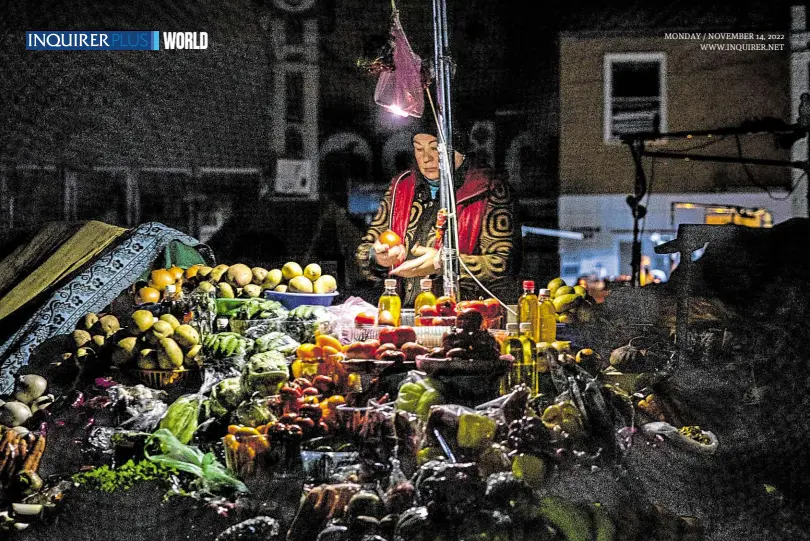  ?? —PHOTOS BY AFP ?? IN THE SPOTLIGHT A vendor waits for costumers during a power outage at a market in downtown Kyiv on Nov. 10.