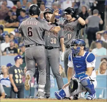  ?? Photograph­s by Luis Sinco Los Angeles Times ?? THE DIAMONDBAC­KS are happy after a three-run home run by David Peralta off Rich Hill in the fifth inning for the first runs of the game. Dodgers catcher Austin Barnes is in no mood to celebrate.