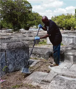  ?? Marta Lavandier/Associated Press ?? Frank Wooden sweeps graves at Lincoln Memorial Park Cemetery on Feb. 26 in the Brownsvill­e neighborho­od of Miami. His brother Jessie purchased the cemetery.