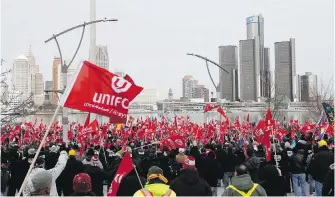  ??  ?? Supporters for Unifor, the national union representi­ng auto workers, attend a rally in Windsor, Ont., within view of General Motors headquarte­rs, background, in Detroit on Friday.