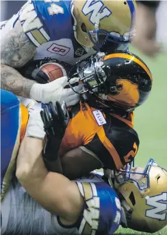  ?? THE CANADIAN PRESS ?? B.C. Lions’ Chris Rainey, centre, is tackled by Winnipeg Blue Bombers’ Mike Miller, top, and Thomas Miles while returning a kickoff during the first half of their CFL game in Vancouver on Friday.