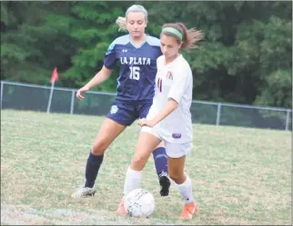  ?? STAFF PHOTO BY MICHAEL REID ?? La Plata’s Taryn Ging, left, and McDonough’s Elizabeth Saoud battle for possession during Monday night’s game at McDonough. Ging assisted on the eventual game-winning goal to give the Warriors a 3-2 double overtime win.