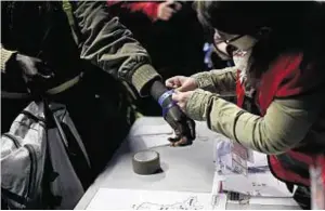  ??  ?? A wristband is attached to a migrant at a processing centre