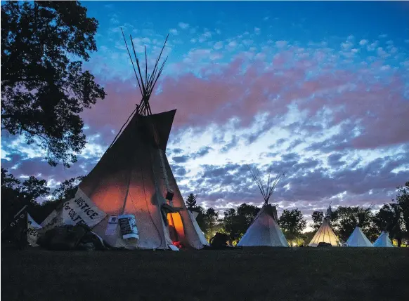  ?? BRANDON HARDER ?? What started out as a single teepee at the Justice For Our Stolen Children camp across from the Saskatchew­an legislatur­e has grown to nine. While the politics surroundin­g the camp are heated, the scene itself is almost serene as summer daylight fades to night over Regina.