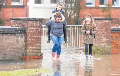  ?? Picture: Steven Brown. ?? The scene on Tuesday as parents rescued their children from Park Road Primary School in Rosyth when flooding engulfed the roads and playground.