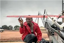  ??  ?? A Zipline worker tinkers with a drone before it is launched on a life-saving mission.