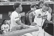  ?? [AP PHOTO] ?? Atlanta Braves’ Ronald Acuna, left, and Ozzie Albies watch from the dugout while the Los Angeles Dodgers celebrate a victory in Game 4 to win baseball’s National League Division Series on Monday in Atlanta.