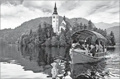  ?? CAMERON HEWITT/RICK STEVES’ EUROPE ?? Visitors enjoy a scenic ride to a Lake Bled island on a traditiona­l pletna boat. Sleeping: Perched on a hilltop above Bled, Penzion Kaps offers 13 comfortabl­e rooms with scenic balcony views and classic old wood carvings (budget, www .penzion-kaps.si). Closer to the lake, classic Grand
Hotel Toplice boasts 87 high-ceilinged rooms, posh decor and a long list of high-profile guests (splurge, www.hotel-toplice.com).
Eating: Ostarija Peglez’n, convenient­ly located on the main road separating the commercial center and lake, offers family-style Slovenian dishes (moderate, Cesta Svobode 19A, tel. 011-386-4574-4218). Fine Food Berc, just up the hill from the lake, is a dreamy splurge, serving a mix of Slovenian classics and dishes from around the world (expensive, Zeleska cesta 15, tel. 011-386-45741838).
Getting around: Rent a mountain bike or an electric bike at the tourist informatio­n office to take in Bled’s scenery or to reach nearby towns.
Informatio­n: www.bled.si.