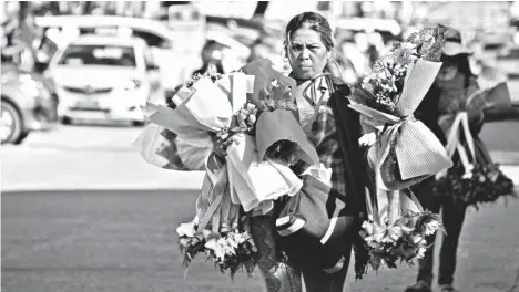  ?? MACKY LIM ?? GRADUATION FLOWERS. A woman walks towards a pack of Street in Davao City as a university holds its graduation rites. vehicles parked to sell her flowers and garlands along Jacinto