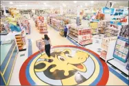  ?? File photo ?? A woman pushes a shopping cart over a graphic of Toys “R” Us mascot Geoffrey the giraffe in Raritan, N.J.