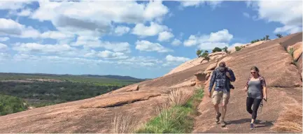  ??  ?? Visitors take the steep walk down from Enchanted Rock at a state natural area near Fredericks­burg, Texas.