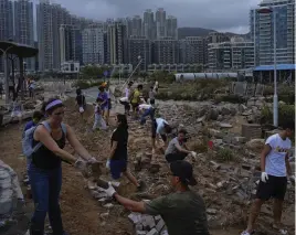  ?? — AP ?? People clean debris caused by Typhoon Mangkhut on the waterfront in Hong Kong on Monday.