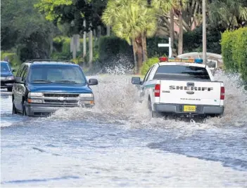  ?? ADAM SACASA/STAFF ?? A Sheriff's pickup truck passes an SUV in a flooded portion of Boca Chase Drive Thursday morning in West Boca.