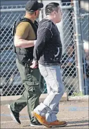  ?? Rogelio V. Solis Associated Press ?? A MAN is taken into custody as federal immigratio­n officials raid a Koch Foods Inc. plant in Morton, Miss.