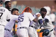  ?? CARLOS OSORIO/AP ?? Detroit Tigers’ Akil Baddoo, right, is swarmed by teammates after driving in the game-winning run during the 10th inning against the Minnesota Twins on Tuesday in Detroit.