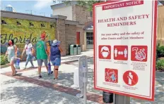  ?? JOHN RAOUX/AP ?? Signs remind patrons to wear masks as they stroll through the Disney Springs shopping, dining and entertainm­ent complex Tuesday in Lake Buena Vista, Fla.