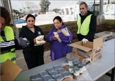  ?? PHOTOS BY DAI SUGANO — STAFF PHOTOGRAPH­ER ?? Stephanie Garcia, center, and her friend, Monica Sepulveda, center left, both of San Jose, receive food donations during Second Harvest of Silicon Valley's grocery distributi­on at Mayfair Community Center in San Jose on Friday.