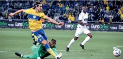  ?? (Ariel Shalom) ?? MACCABI TEL AVIV forward Aleksandar Pesic scores his team’s first goal past Maccabi Petah Tikva ’keeper Arik Yanko in the yellow-and-blue’s 3-1 victory at Bloomfield.