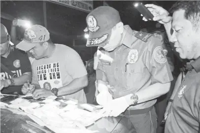  ?? (NCRPO photo) ?? NATIONAL Capital Region Police Office (NCRPO) director Chief Supt. Guillermo Eleazar inspects some 500 grams of shabu with a street value of ₱3,400,000 seized from a lady drug courier during a buy-bust operation at the parking lot of a popular mall in Parañaque City, Thursday night.