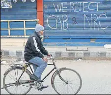  ?? AFP FILE ?? A man cycles past graffiti against the new citizenshi­p law and the National Register of Citizens.