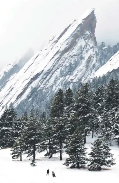  ??  ?? Fog rolls over the Flatirons in Boulder as people hike in Chautauqua Park.