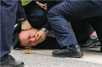  ?? Associated Press ?? Police officers pin down and arrest a protester in Shanghai on Sunday. Authoritie­s eased antivirus rules in scattered areas but affirmed China’s severe “Zero COVID” strategy Monday.