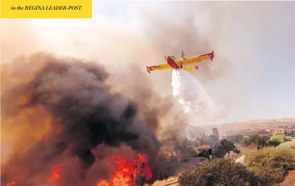  ?? RINGO H.W. CHIU / THE ASSOCIATED PRESS ?? An air tanker drops water on a fire along the Ronald Reagan Freeway in Simi Valley, Calif., on Monday. Authoritie­s in the state are searching for more than 200 missing people, some of whom are suspected to have been killed in a blaze that burned so hot that it melted metal off cars.