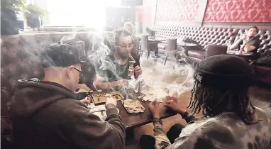  ?? AP ?? In this March 1, 2018 photo, Rick Thompson (clockwise, from left) Keith Baskervill­e and Xavier Baskervill­e smoke marijuana while sitting in a booth in the smoking lounge at Barbary Coast Dispensary in San Francisco.