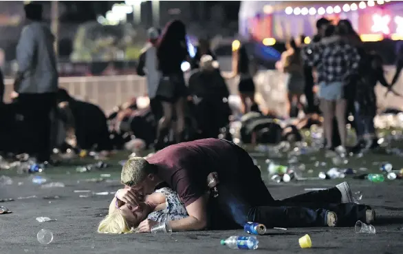  ?? DAVID BECKER / GETTY IMAGES ?? A man lays on top of a woman in the aftermath of the shooting massacre at a country music concert in Las Vegas on Sunday. At least 59 people were killed.