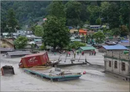  ?? PRAKASH ADHIKARI — THE ASSOCIATED PRESS ?? A vehicle that was washed away lies on top of a submerged building after flash floods triggered by sudden heavy rainfall swamped Rangpo town in Sikkim, India, on Thursday.