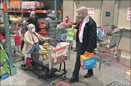  ?? Mel Melcon Los Angeles Times ?? SHELVES in stores were emptied amid panic buying. Above, customers wait in a long checkout line at Costco in the Village at Topanga on Friday in Los Angeles.