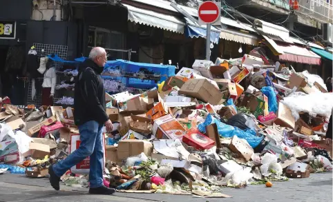  ?? (Marc Israel Sellem/The Jerusalem Post) ?? A MAN walks past a heap of garbage outside Jerusalem’s Mahaneh Yehuda Market during the three-day municipal strike that began on January 29.