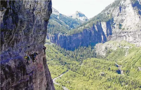  ?? John Briley photos / For the Washington Post ?? A group of hikers works its way along the Main Event, the most exposed section of the Telluride via ferrata, a mountainee­ring route with iron hand and foot holds, and sections of safety cable, to help people across.