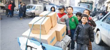  ?? (Bassam Diab/UNHCR/Reuters) ?? CHILDREN PUSH a cart carrying relief items provided by UNHCR and other UN partners in the east Aleppo neighborho­od of Tariq al-Bab yesterday.