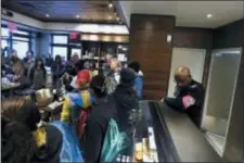  ?? JACQUELINE LARMA — THE ASSOCIATED PRESS ?? A plain-clothed police officer, right, mans a position behind the counter at the Starbucks that has become the center of protests Monday in Philadelph­ia.