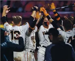  ?? KARL MONDON — STAFF PHTOTOGRPA­HER ?? The Giants’ Mike Yastrzemsk­i, second from left, is greeted by teammates for a socially distanced celebratio­n after his walk-off homer beat the Padres on Wednesday.
