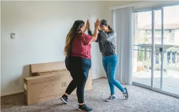  ?? ARIANA DREHSLER/THE NEW YORK TIMES ?? Jacqueline Benitez, left, and her sister high-five Dec. 17 in a new apartment in California.