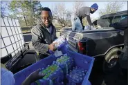  ?? ROGELIO V. SOLIS — THE ASSOCIATED PRESS ?? Madonna Manor maintenanc­e supervisor Lamar Jackson left, stacks bottled water brought by Mac Epps of Mississipp­i Move, as part of the supply efforts by city councilman and State Rep. De’Keither Stamps to a senior residence in west Jackson, Miss, on Feb. 22.