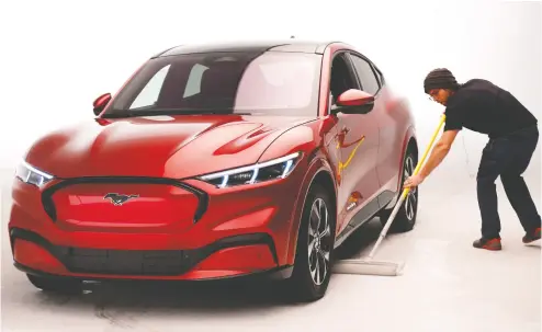  ?? REBECCA COOK / REUTERS FILES ?? Ford Motor Co. shows off the electric Mustang Mach-e vehicle in 2019. Ford and other automakers are racing to shift
their gasoline-powered lineups to all electric power. Ford’s sales target for 2030 translates to over 1.5 million EVS.