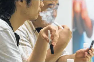  ?? Shiho Fukada / Washington Post ?? Customers try a new tobacco device at an IQOS store in Tokyo. Since its introducti­on, IQOS has captured 10 percent of the tobacco market in Japan, a fact not lost on U.S. tobacco companies.