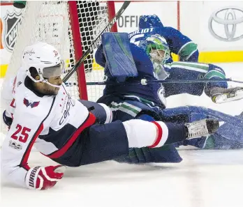  ?? THE CANADIAN PRESS/RIC ERNST ?? Vancouver Canucks goalie Anders Nilsson is knocked over by Washington Capitals forward Devante Smith-Pelly during the second period on Thursday night.