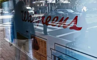  ?? BRENDAN SMIALOWSKI/AFP VIA GETTY IMAGES ?? A pedestrian was reflected in a window of Walgreens in Washington, D.C., on Nov. 2.