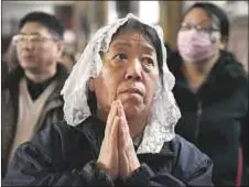  ?? AFP Photo/ Greg Baker ?? Una mujer, en oración, en Pekín, este Jueves Santo