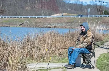  ?? Michael M. Santiago/Post-Gazette ?? David Connolly of McCandless spends an afternoon fishing for rainbow trout on Thursday at North Park Lake in McCandless. Fishing is classified as a "life-sustaining" activity.