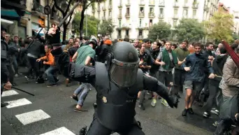  ?? − Associated Press: Manu Fernandez ?? Un policier antiémeute frappe des électeurs près d’une école où est tenu un bureau de scrutin, dimanche, à Barcelone.