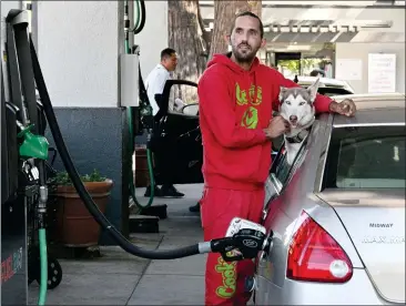  ?? PHOTOS BY SHERRY LAVARS — MARIN INDEPENDEN­T JOURNAL ?? James Ahrenholz of San Rafael pumps gas while his dog Aurora waits in the car Friday at Fuel 24:7in San Rafael. Ahrenholz paid $40 for half a tank of gas.